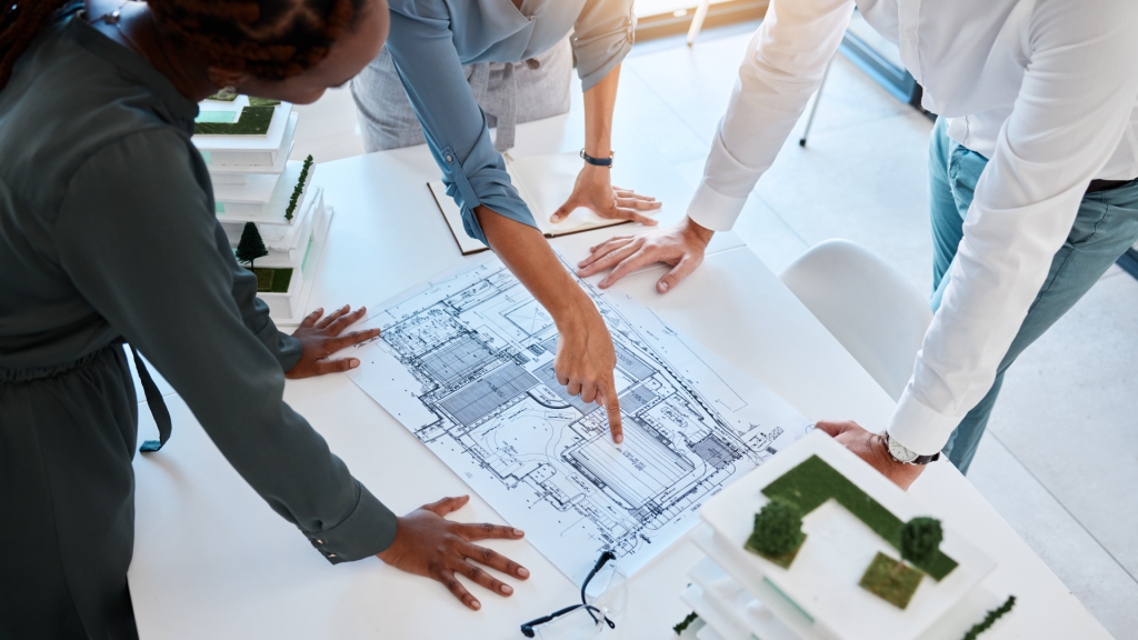 Architects reviewing blueprints and sustainable building models during a planning meeting