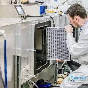 GLP Filter Testing for Pathogen Removal Lab technician inspecting HEPA filter for airborne pathogen testing in Airmid Healthgroup chamber