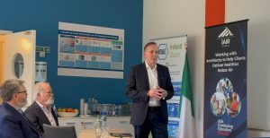Dr. John Ryan speaking at the ASHRAE Ireland Technical Seminar at Airmid Healthgroup, with banners showcasing iAIR Academy and the IRIAE Ireland Chapter.