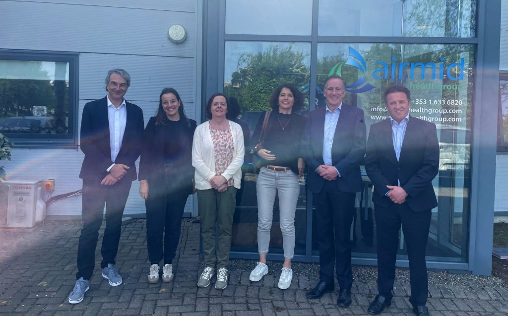 Delegates from Swissatest Testmaterialien AG stand with Airmid Healthgroup leadership outside the Dublin lab. The photo captures a moment of international scientific collaboration focused on appliance hygiene and indoor air quality testing.