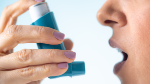 Close-up of a woman using an asthma inhaler to manage symptoms, and indoor air quality testing