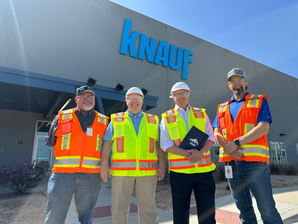 Dr. John McKeon with three Knauf team members in hi-vis vests outside the Knauf McGregor manufacturing facility in Texas