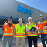 Dr John McKeon and Knauf Team Outside McGregor Facility Texas | Airmid Healthgroup Dr. John McKeon with three Knauf team members in hi-vis vests outside the Knauf McGregor manufacturing facility in Texas