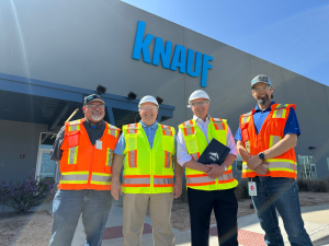 Dr. John McKeon with three Knauf team members in hi-vis vests outside the Knauf McGregor manufacturing facility in Texas