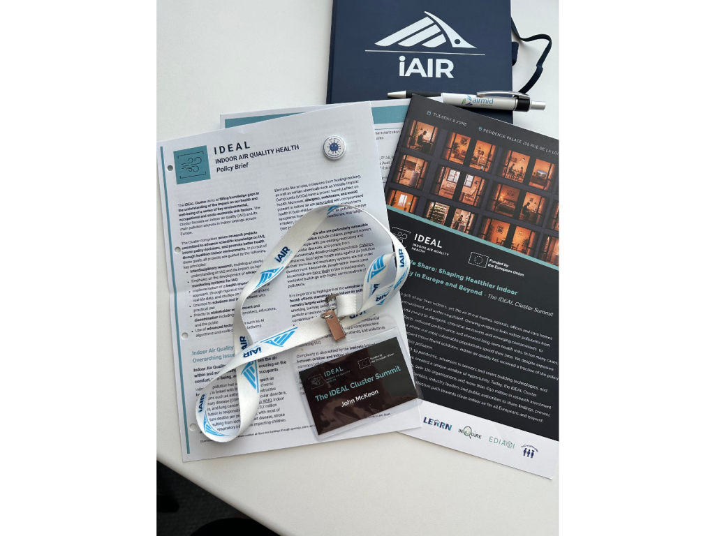 IDEAL Cluster Summit materials including an iAIR Institute lanyard, IDEAL Indoor Air Quality Health policy brief, and event programme for The Air We Share summit in Brussels