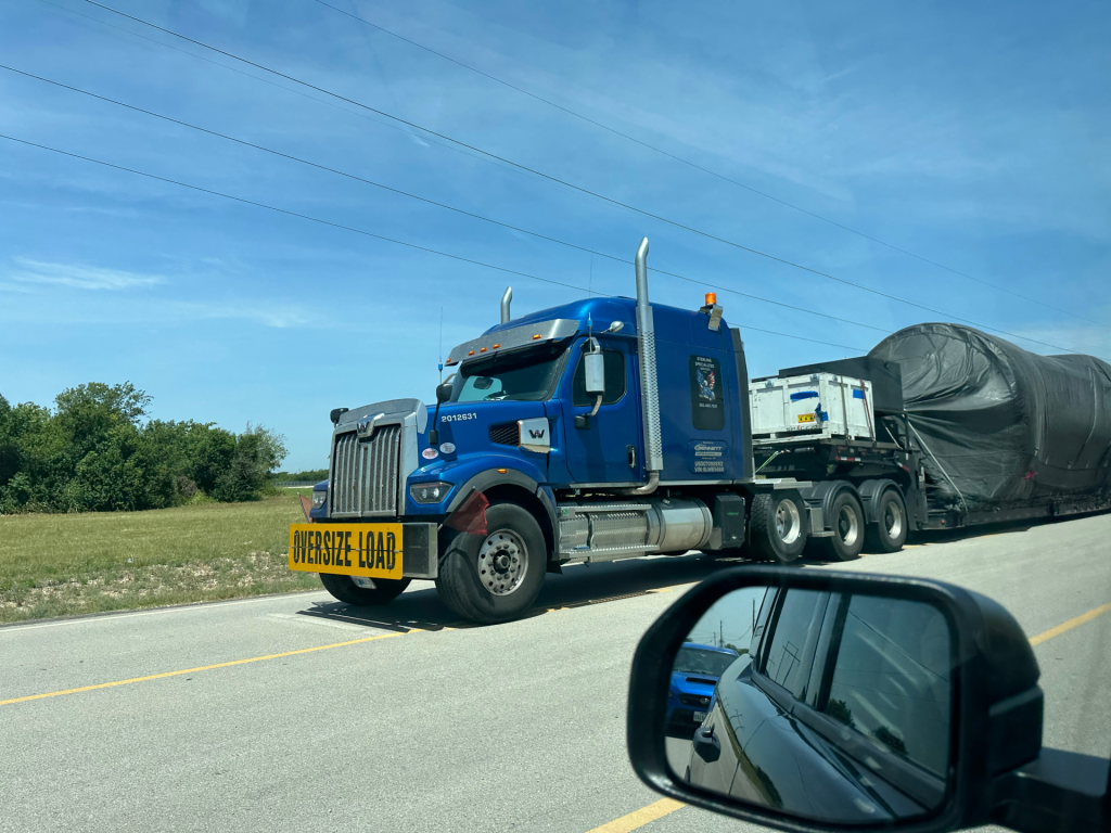 Oversize Load Transport Near SpaceX McGregor Texas | Airmid Healthgroup Oversize load truck transporting large equipment on the highway near McGregor, Texas, close to the SpaceX facility