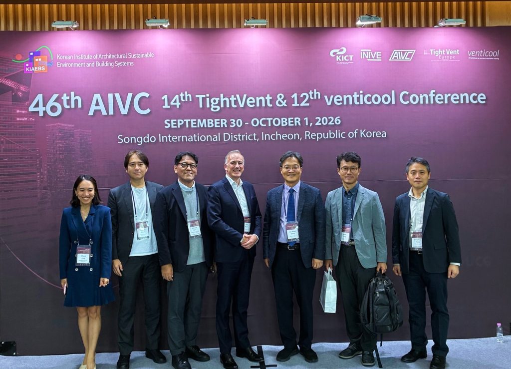 Dr. John Ryan of Airmid healthgroup standing with ASHRAE South Korea Chapter officers and AIVC 2026 conference organisers in front of the 46th AIVC Conference backdrop in Songdo, Republic of Korea
